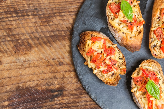 Włoski bruschetta z pieczonymi pomidorami, mozzarellą i