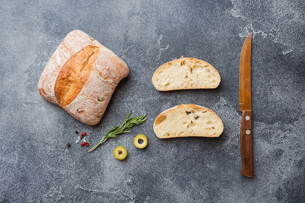 Zdjęcie włoski ciabatta chleb z oliwkami i rozmarynami na ciemnym betonowym tle