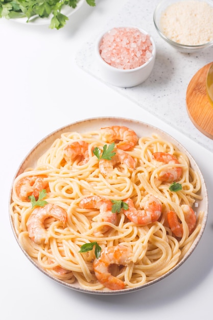 włoski makaron fettuccine lub spaghetti w kremowym sosie serowym z krewetkami lub krewetkami na talerzu