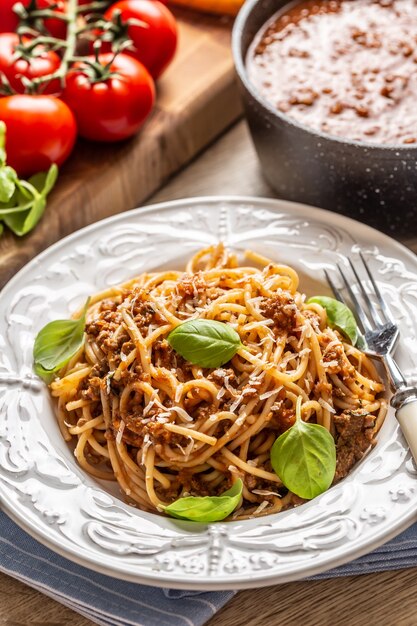 Włoski makaron spaghetti bolognese podawany na białym talerzu z parmezanem i bazylią.