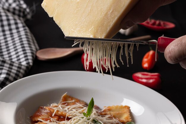 Zdjęcie włoski makaron spaghetti na białym talerzu otoczonym różnymi składnikami i przyborami kuchennymi na czarnym stole
