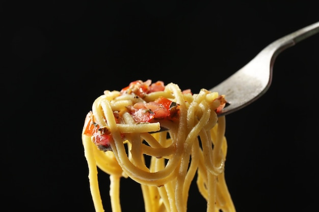 Włoski makaron spaghetti na rozwidleniu na czarnym tle