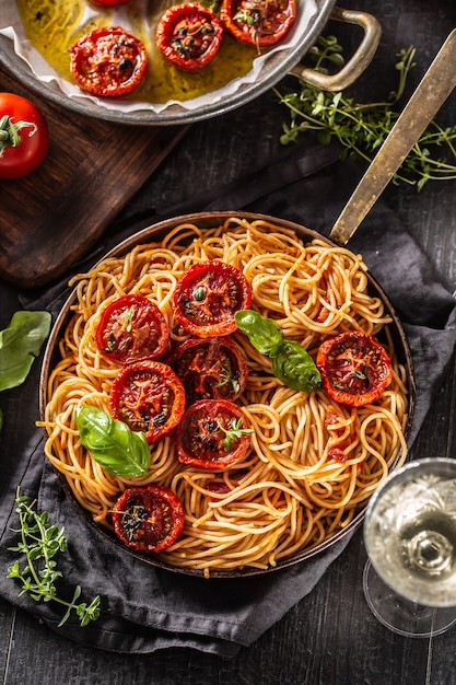 Włoski makaron spaghetti z pieczonymi pomidorami, bazylią, tymiankiem oregano i białym winem - Top of view.