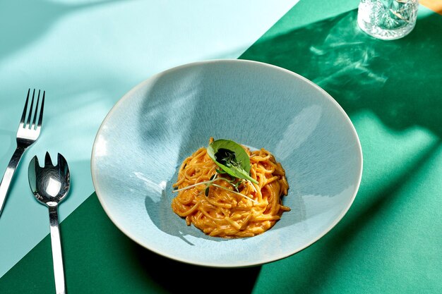 Włoski makaron spaghetti z sosem pomidorowo-serowym w talerzu z jasnym tłem. Selektywne skupienie, twarde cienie