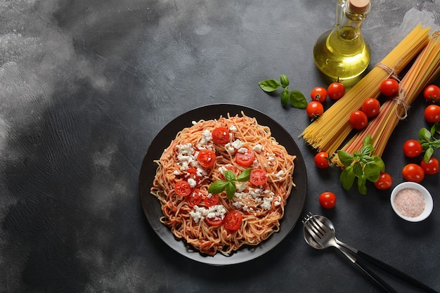 Włoski makaron spaghetti z sosem pomidorowym, mozzarellą, pomidorkami koktajlowymi i bazylią