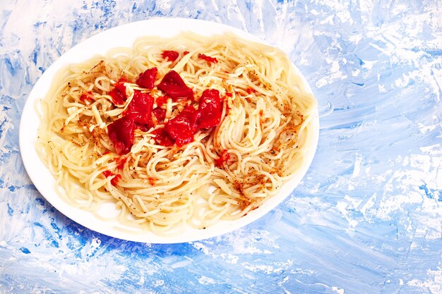Zdjęcie włoski makaron z sosem pomidorowym talerz włoskiego makaronu na niebieskim tle z sosem pomidorowym