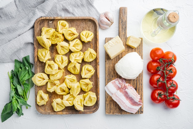 Włoskie domowe tortellini ze składnikami, szynka, bazylia, pesto, zestaw mozzarelli, na drewnianej tacy, widok z góry na płasko