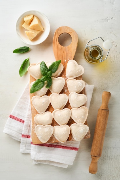 Zdjęcie włoskie ravioli w kształcie serca pyszne surowe ravioli z mąką i bazylią na białym tle składniki gotowania żywności tło pomysły na obiad na święto walentynek lub dzień matki