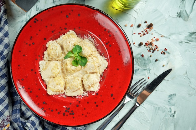 Włoskie tradycyjne ravioli z mięsem mielonym w kremowo-orzechowym sosie na białym talerzu