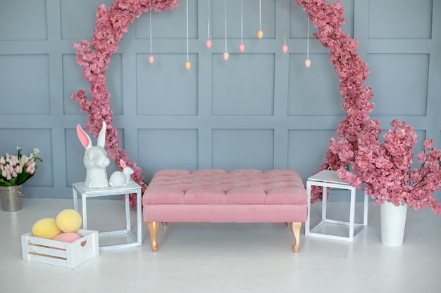 wnętrze domu z dekoracją wielkanocną z różową sofą i wieńcem kwiatów na jasnoniebieskim tle