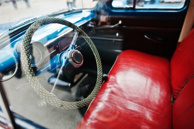 Zdjęcie wnętrze i kierownica z czerwonymi skórzanymi siedzeniami na starym samochodzie retro vintage