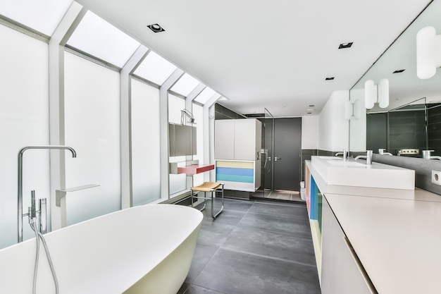 Wnętrze jasnej toalety z czystą wanną i kolorowymi szafkami z umywalkami w nowoczesnym mieszkaniu