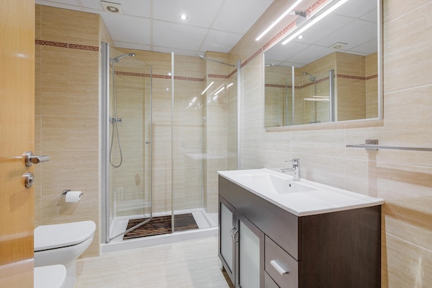 Wnętrze łazienki w jasnych tonacjach z toaletą kabinową i umywalką