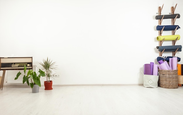 Wnętrze nowoczesnego minimalistycznego studia jogi Maty do jogi i rośliny doniczkowe na tle białej ściany