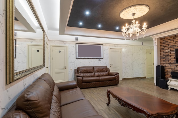 Wnętrze nowoczesnego salonu z dwiema brązowymi skórzanymi sofami, ogromnym lustrem w ramie i an