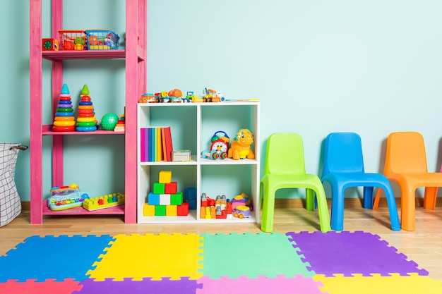 Wnętrze pokoju zabaw w przedszkolu Szafki wypełnione są różnymi zabawkami i innymi kolorowymi meblami w pokoju