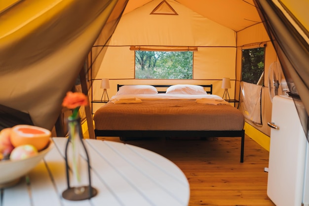 Wnętrze przytulnego otwartego namiotu glampingowego ze światłem wewnątrz podczas zmierzchu Luksusowy namiot kempingowy na letnie wakacje i wakacje Koncepcja stylu życia