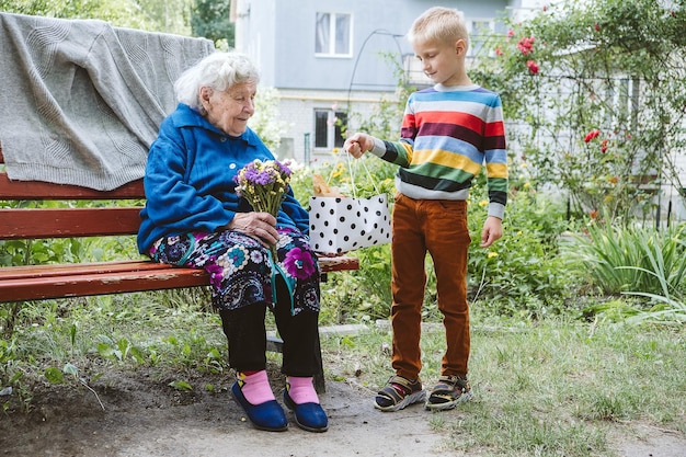 Wnuk chłopczyk dający kwiatek babci wnuczka i babci spędzających czas razem z babcią