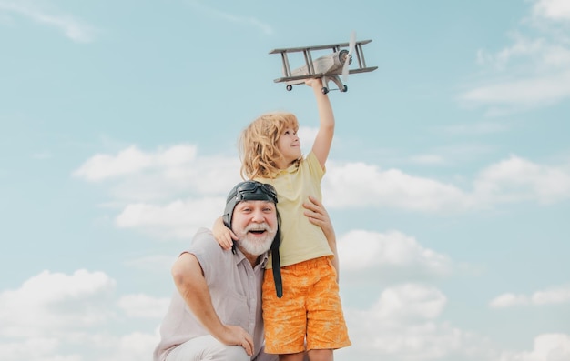 Wnuk dziecko i dziadek z zabawkowym samolotem odrzutowym na tle nieba dziecko pilot pilot z samolotem dre