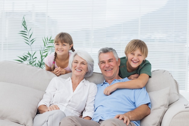 Wnuki i dziadkowie siedzi na kanapie
