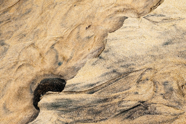 Woda i piasek tworzą graficzny wzór na plaży w północnej Bretanii