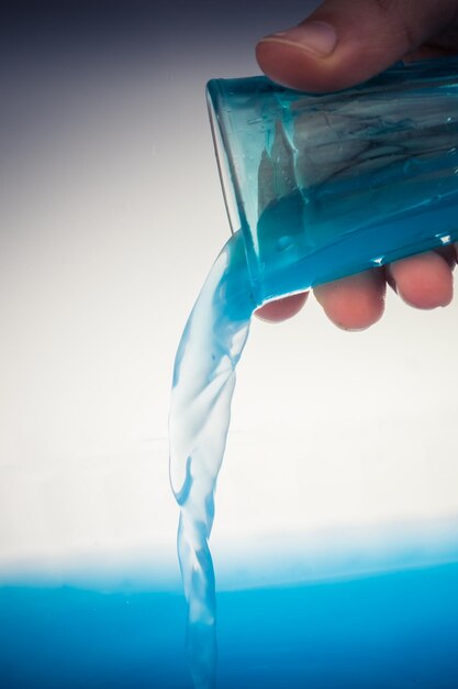 Zdjęcie woda wylewająca się z niebieskiego szkła w dłoni