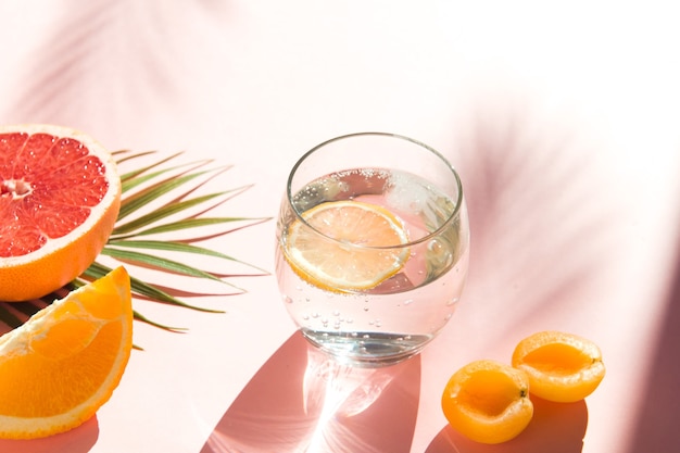 woda z lodem i cytryną fajne letnie napoje zdrowe jedzenie owoce i szkło sodowe na różowym tle