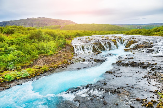 Wodospad Bruarfoss z błękitną wodą o zachodzie słońca. Południowa Islandia. Piękny letni krajobraz