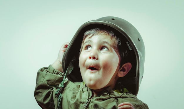 Wojownik, Śliczny chłopczyk, bawiący się w domu, bawiąc się w wojny i pokój, zabawne dziecko ubrane w czapkę wojskową i gogle