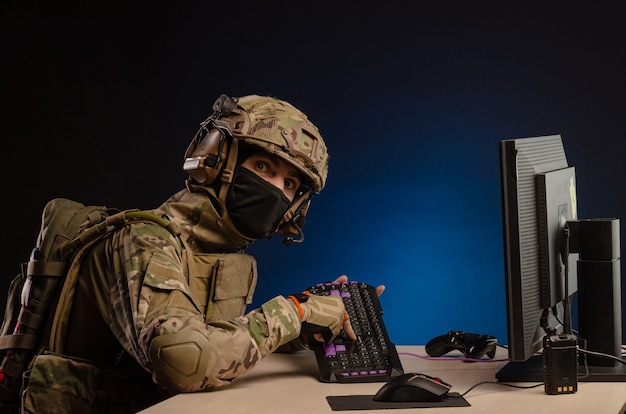 Wojsko w mundurze siedzące przy komputerze prowadzi cyberwojnę
