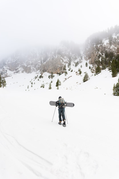 Wolny jeździec z rakietami śnieżnymi i snowboardem na plecach.