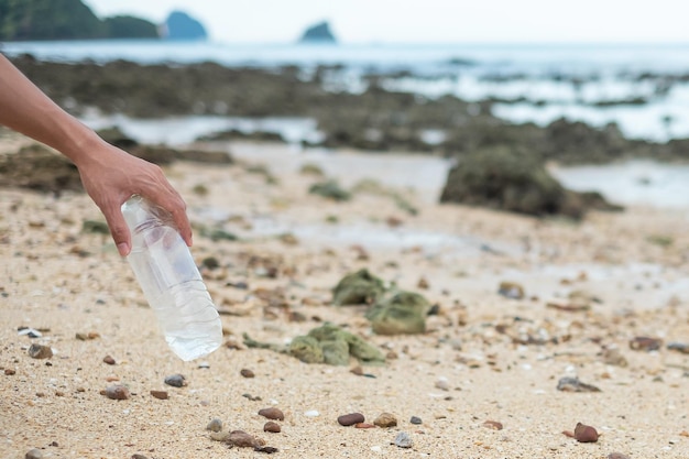 Wolontariusz ręcznie odbiera śmieci plastikowe butelki na śmieci na plaży Ekologia Zanieczyszczenie środowiska i koncepcja problemu ekologicznego