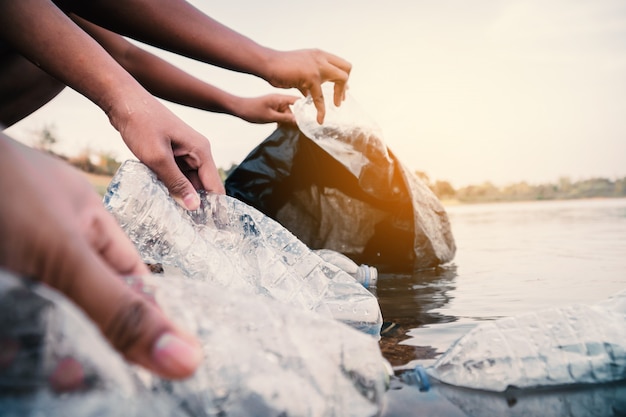 Wolontariusz zbiera plastikową butelkę w rzece, chroni środowisko przed koncepcją zanieczyszczenia.