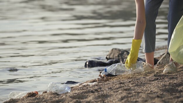 Wolontariusz zbiera plastikowe śmieci w parku. recyklingu plastikowej butelki ekologia koncepcja oczyszczania niewyraźne tło. Czyste rękawiczki wolontariuszy zbiera plastikowe butelki i szklanki w worku na śmieci.