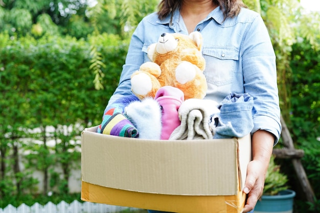 Wolontariusz zbiera tkaniny i lalki w kartonowym pudełku do darowizny