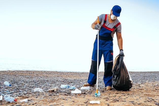 Wolontariusz Zbierający śmieci Na Plaży Za Pomocą Przedłużacza Zasięgu