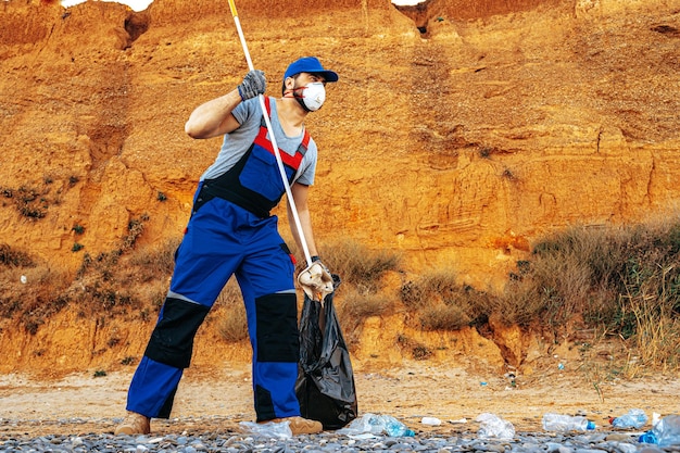 Zdjęcie wolontariusz zbierający śmieci na plaży za pomocą przedłużacza zasięgu