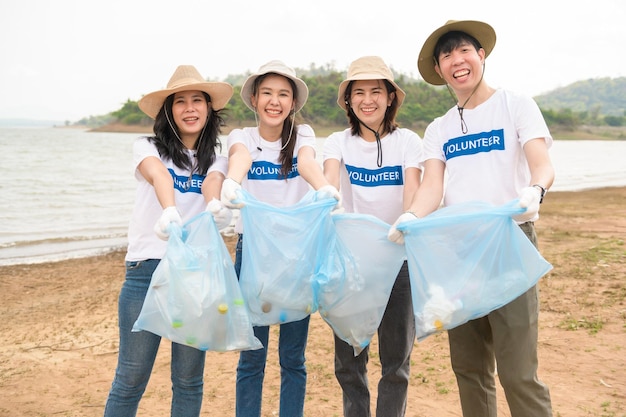 Wolontariusze z azjatyckiej społeczności młodzieżowej przy użyciu worków na śmieci sprzątają park przyrody