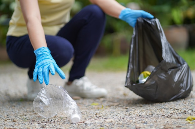 Zdjęcie wolontariuszka charytatywna kobieta trzymająca czarną torbę na śmieci i plastikowe butelki śmieci do recyklingu do sprzątania w parku koncepcja wolontariatu ponowne wykorzystanie i pomoc wolontariuszy