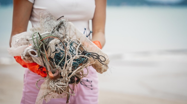 Wolontariuszka-ekolożka czyści plażę nad brzegiem morza z plastiku i innych odpadów