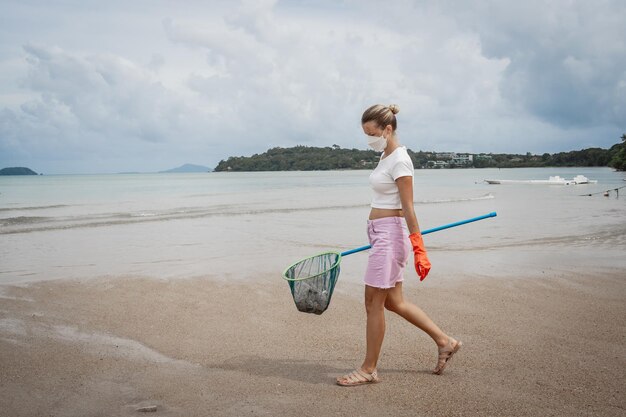 Wolontariuszka-ekolożka czyści plażę nad brzegiem morza z plastiku i innych odpadów