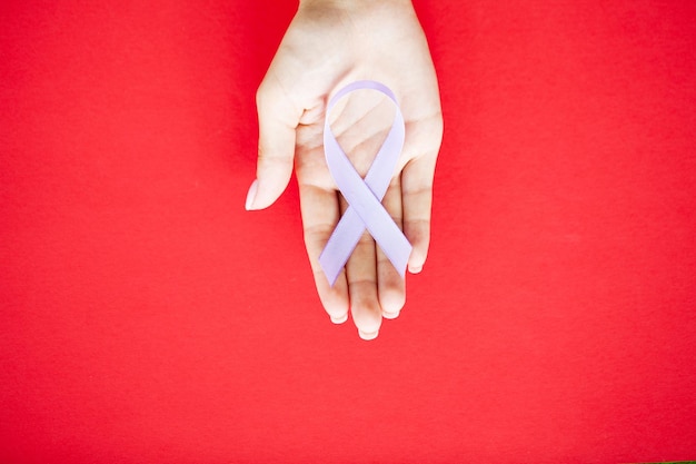 Womans ręce trzymając fioletową wstążkę świadomości przemocy domowej