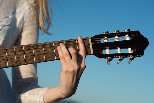 Womans ręka gra na gitarze akustycznej zbliżenie instrumentu