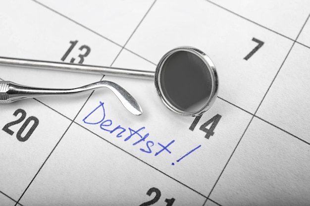 Zdjęcie word dentist w zbliżeniu kalendarza i narzędzi dentystycznych