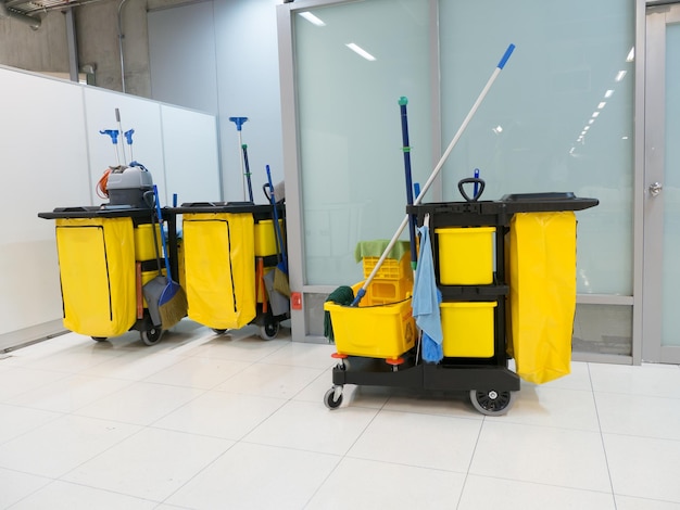 Wóz czyszczący na stacji, wózek z narzędziami do czyszczenia i żółte wiadro do mopa czekają na czyszczenie.