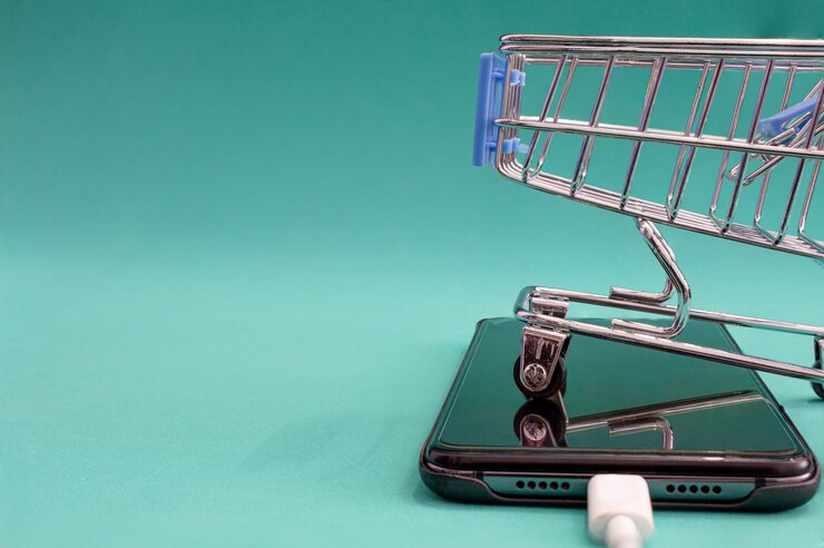 Zdjęcie wózek i telefon na zielonym tle z refleksji koncepcje sprzedaży i zakupów.