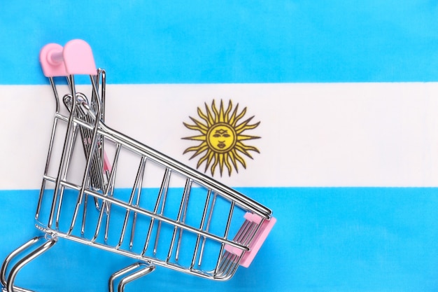 Wózek Mini Supermarket Na Niewyraźne Tło Flaga Argentyny. Koncepcja Zakupów.