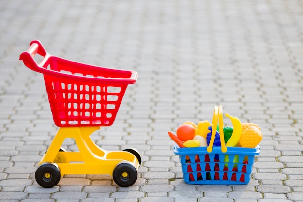 Wózek na zakupy i kosz z zabawkowymi owocami i warzywami.