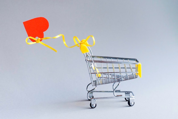 Wózek na zakupy z sercem na szarym tle Szablon promocji i zakupów Walentynki Przestrzeń do kopiowania