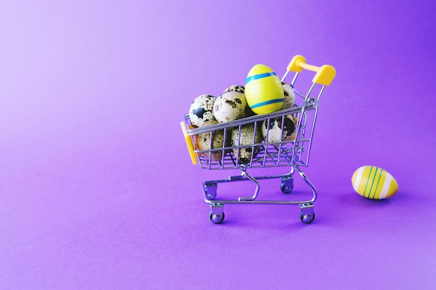 Wózek z zabawkami z supermarketu wypełniony jest jajkami wielkanocnymi na fioletowym tle